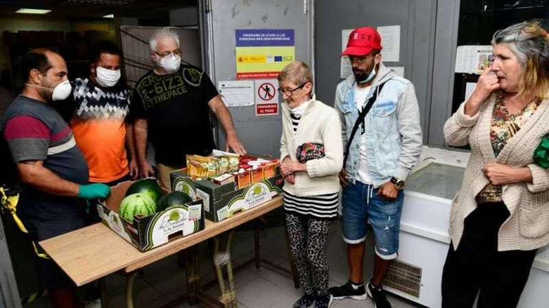 Voluntarios de la Asociación Guillermo Casañas Gil entregan un lote de comida a una señora en su sede (Foto Arcadio Suárez/C7)